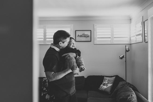 black and white image of father carrying toddler with Perth newborn lifestyle photographer