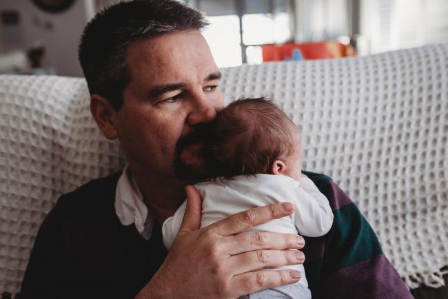 Father holding newborn baby on his shoulder with Perth newborn lifestyle photographer
