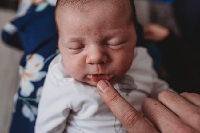 mother poking lip down of newborn baby with Perth newborn lifestyle photographer