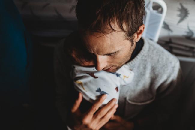 Father holding newborn baby on chest with lifestyle newborn photographer Perth