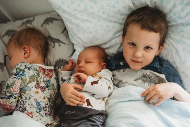 Three children in bed with lifestyle newborn photographer Perth