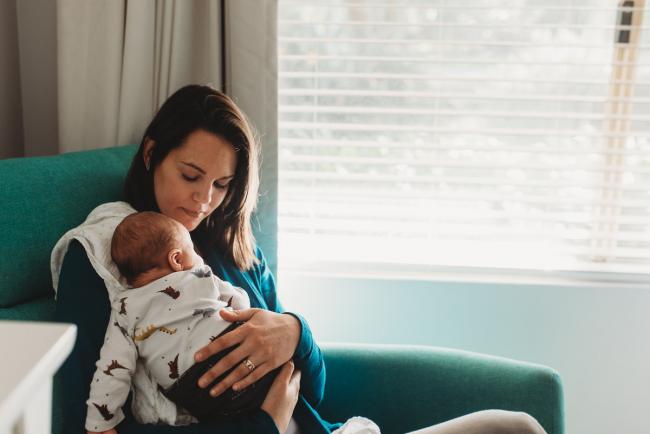 Mother sitting on chair with new baby with lifestyle newborn photographer Perth