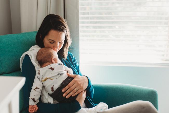 Mother sitting on chair with new baby with lifestyle newborn photographer Perth