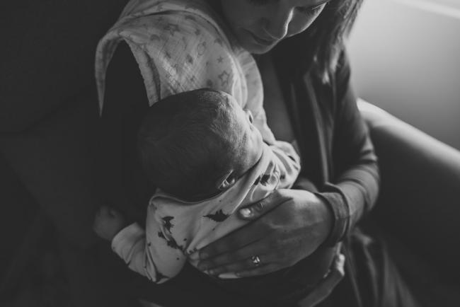 Black and white image of mother holding new baby with lifestyle newborn photographer Perth