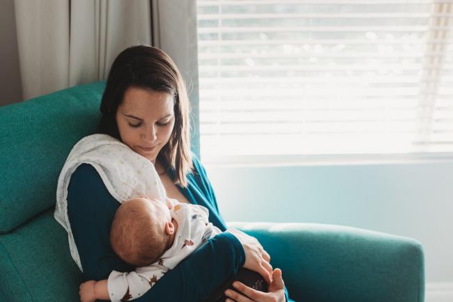 Mother holding sleeping baby with lifestyle newborn photographer Perth