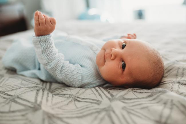Newborn baby on bed looking at the camera with lifestyle newborn photographer Perth