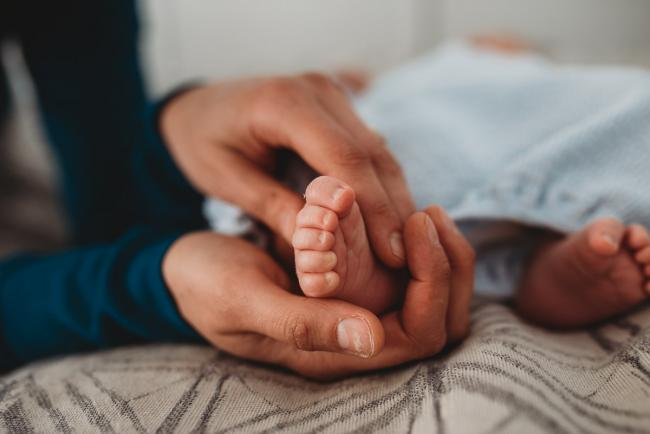 Mother holding newborn baby's foot with lifestyle newborn photographer Perth