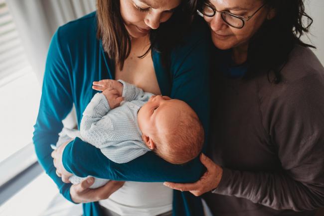 Mother holding new baby as grandmother cuddles in with lifestyle newborn photographer Perth