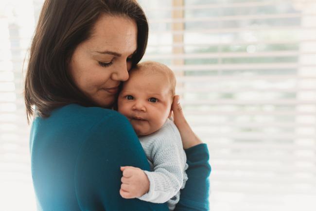 Mother holding baby on her shoulder with lifestyle newborn photographer Perth