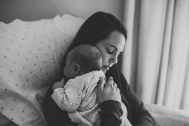 black and white image of mother holding newborn baby on her shoulder with lifestyle newborn photographer Perth
