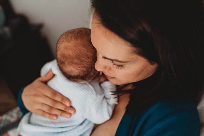 Mother holding baby on her shoulder with lifestyle newborn photographer Perth