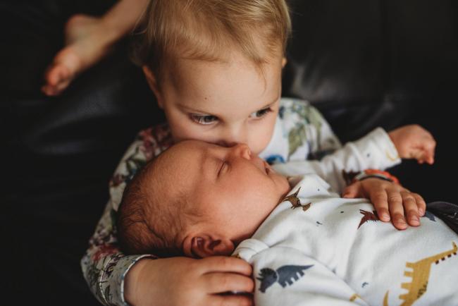 Little girl holding baby brother with lifestyle newborn photographer Perth
