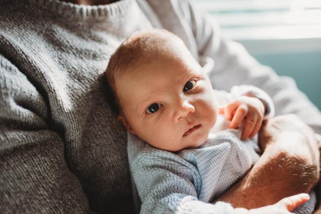 Baby looking at camera with lifestyle newborn photographer Perth