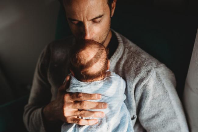 Father kissing newborn baby with lifestyle newborn photographer Perth