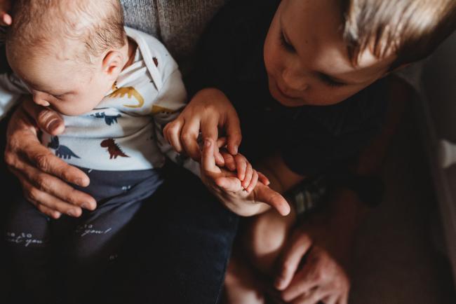 Little boy holding baby brothers hand with lifestyle newborn photographer Perth