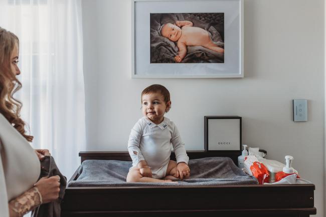 Little boy on change table smiling at his mother with Perth Events Photographer