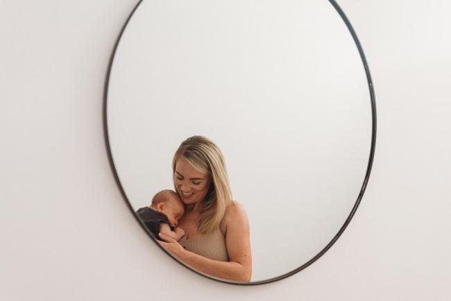 mother in front of mirror with newborn baby with lifestyle newborn photographer Perth
