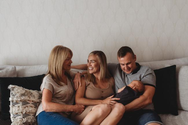 Mother, father and grandmother sitting on couch with newborn baby with in-home lifestyle newborn photographer Perth