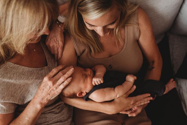 mother and grandmother on couch with newborn baby with lifestyle newborn photographer Perth