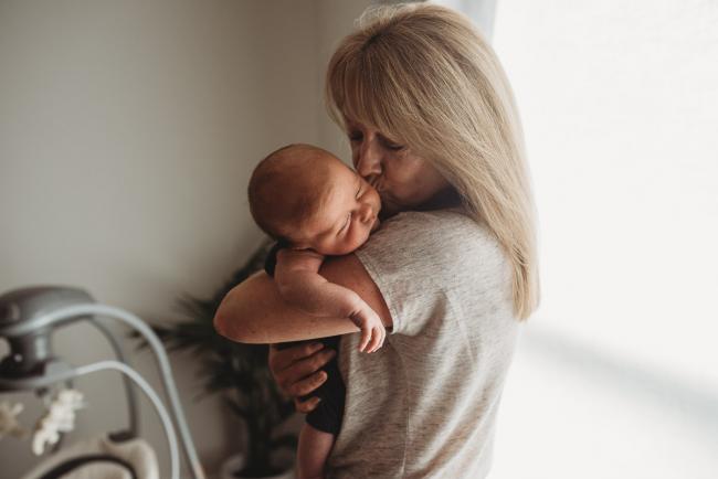 grandmother kissing newborn baby by window with lifestyle newborn photographer Perth