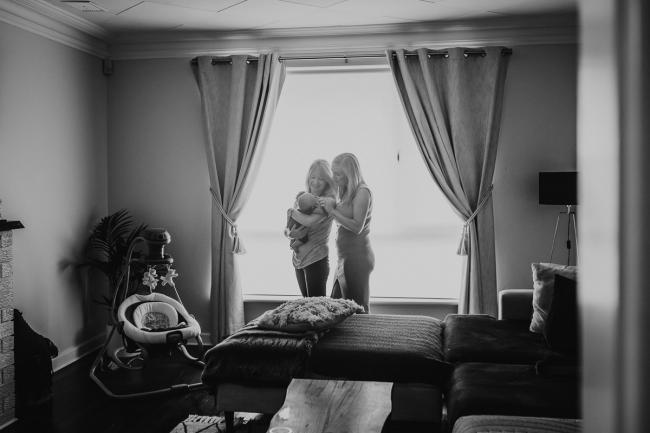 Lifestyle-Newborn-Photographer-Perth-20-of-69 Black and white image of mother and grandmother standing by window with newborn baby with in-home lifestyle newborn photographer Perth