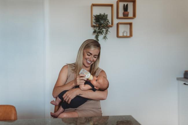 Mother bottle feeding newborn baby with in-home lifestyle newborn photographer Perth