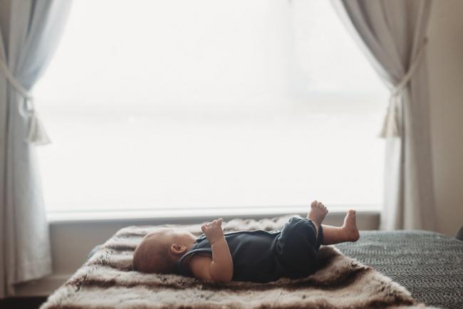 newborn baby on couch in front of window with lifestyle newborn photographer Perth