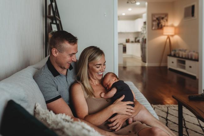 Lifestyle-Newborn-Photographer-Perth-6-of-69 mother and father smiling at their newborn baby on couch with in-home lifestyle newborn photographer Perth