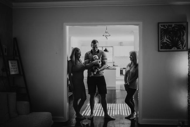 Lifestyle-Newborn-Photographer-Perth-69-of-69 black and white image of mother, father, and grandmother standing in doorway with newborn baby with Perth lifestyle newborn photographer