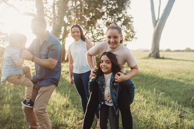 Father lifting son and daughters having piggybacks during Perth family photographer session at Perry's Paddock
