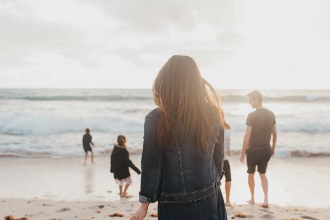 Family-Photographer-Perth-Burns-Beach-14-of-57 Back of mother as she looks at family on beach at Burns Beach with Perth Family Photographer