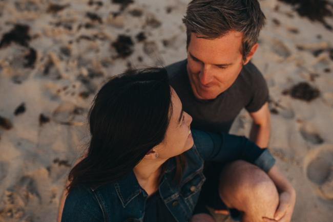 Family-Photographer-Perth-Burns-Beach-16-of-57 Couple looking at each other and smiling at Burns Beach with Perth Family Photographer