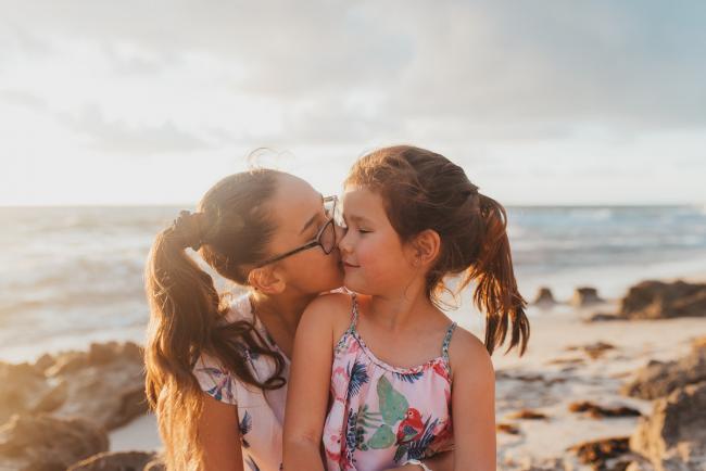 Sister kissing her little sister at Burns Beach with Perth Family Photographer