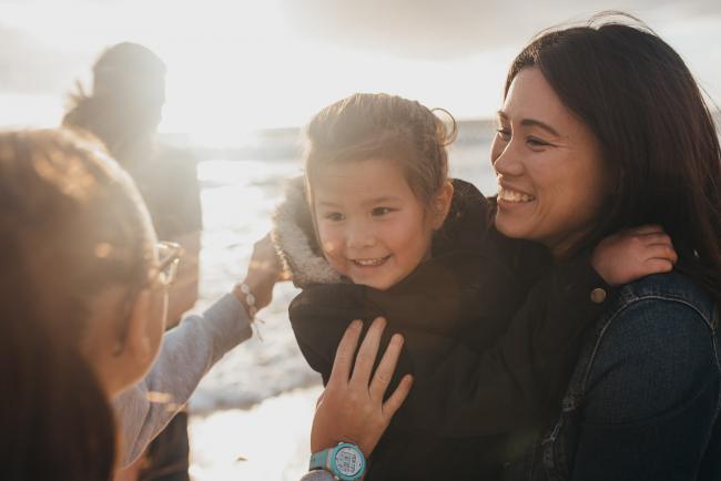 Family-Photographer-Perth-Burns-Beach-2-of-57 Mother holding daughter as other daughter reaches out for her at Burns Beach with Perth Family Photographer