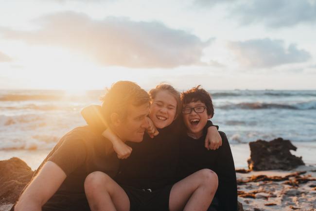 Family-Photographer-Perth-Burns-Beach-31-of-57 Father and two sons with arms around each other at Burns Beach with Perth Family Photographer