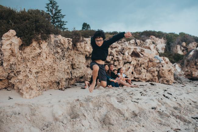 Family-Photographer-Perth-Burns-Beach-49-of-57 Boy jumping on sand at Burns Beach with Perth Family Photographer