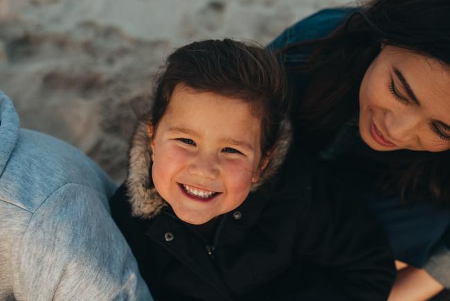Family-Photographer-Perth-Burns-Beach-6-of-57 Little girl smiling up at the camera at Burns Beach with Perth Family Photographer