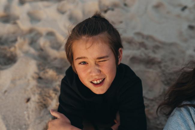Family-Photographer-Perth-Burns-Beach-7-of-57 Little boy winking and smiling up at the camera at Burns Beach with Perth Family Photographer