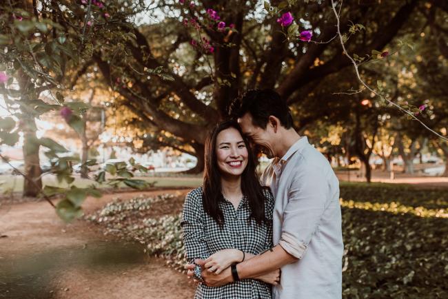 Husband resting head on wife as she smiles at camera during Perth extended family session at Hyde Park with Perth family photographer
