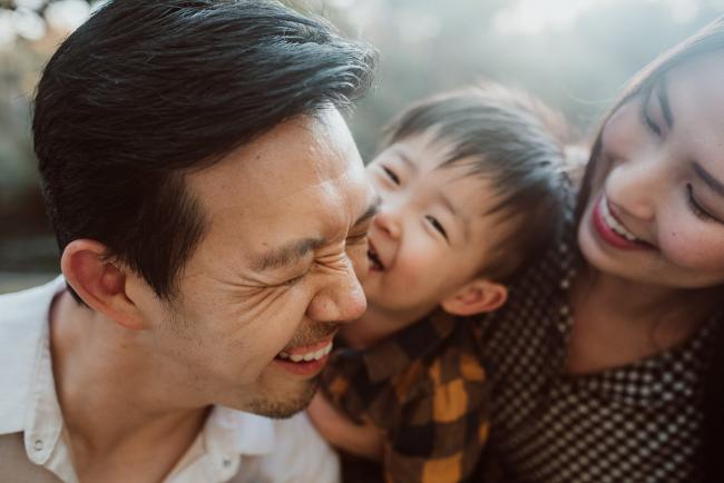 Son kissing father who is laughing during Perth extended family session at Hyde Park with Perth family photographer