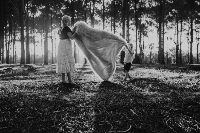 black and white image of mother and son shaking blanket during Perth family photography session at The Pines Wanneroo