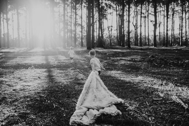 Family-Photographer-Perth-The-Pines-17-of-29 black and white image of brother pulling blanket as chases his brother during Perth family photography session at The Pines Wanneroo