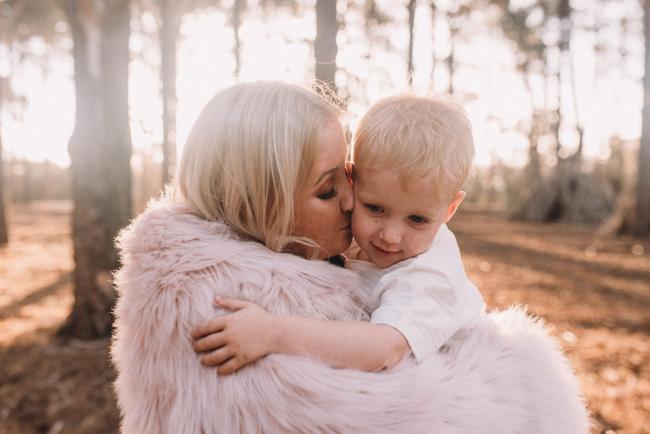 Family-Photographer-Perth-The-Pines-19-of-29 mother kissing son with blanket wrapped around them during Perth family photography session at The Pines Wanneroo