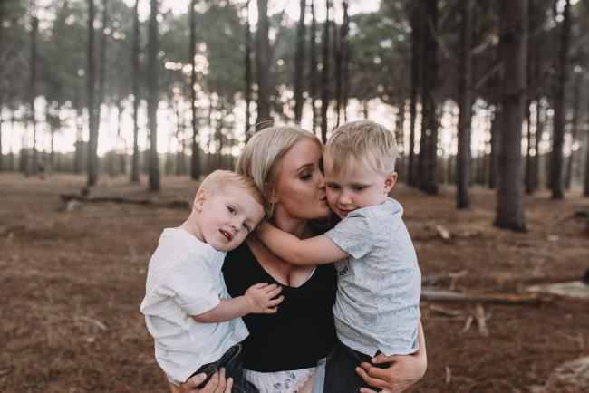 Family-Photographer-Perth-The-Pines-5-of-29 Mother holding two boys and kissing one of them during Perth family photography session at The Pines Wanneroo