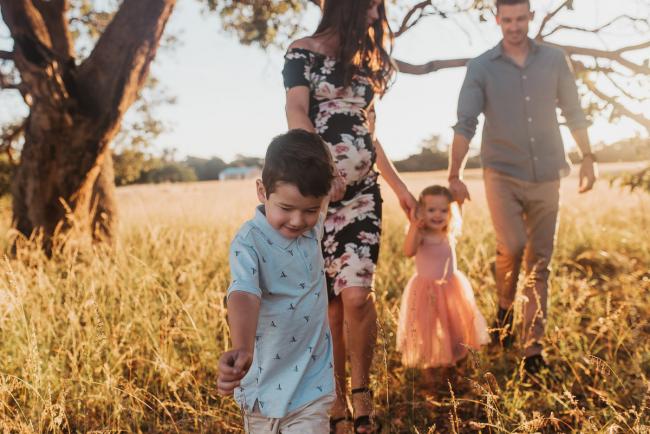 Little boy leading family in a walk during Perth maternity photography session during golden hour at Perry's Paddock