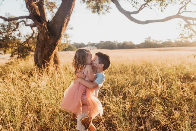 Little boy lifting his sister during Perth maternity photography session during golden hour at Perry's Paddock