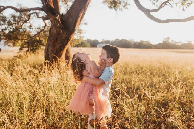 Little boy lifting his sister during Perth maternity photography session during golden hour at Perry's Paddock