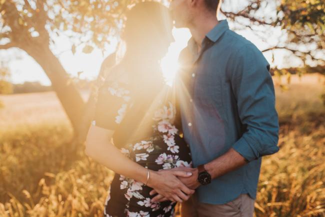 Couple with hands on pregnant tummy during Perth maternity photography session during golden hour at Perry's Paddock