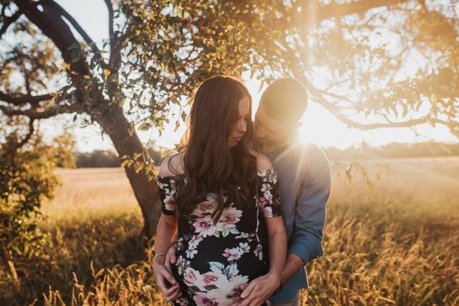 Husband hugging pregnant wife from behind during Perth maternity photography session during golden hour at Perry's Paddock