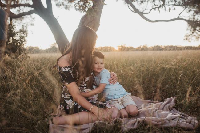 Son cuddling pregnant mother on blanket during Perth maternity photography session during golden hour at Perry's Paddock